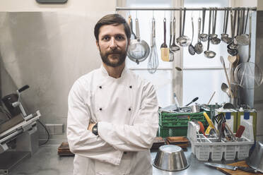 Porträt eines selbstbewussten Kochs mit verschränkten Armen in einer Großküche - MASF20129