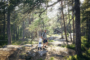 Tochter mit Fischernetz, die an der Hand des Vaters im Wald spazieren geht - MASF20163