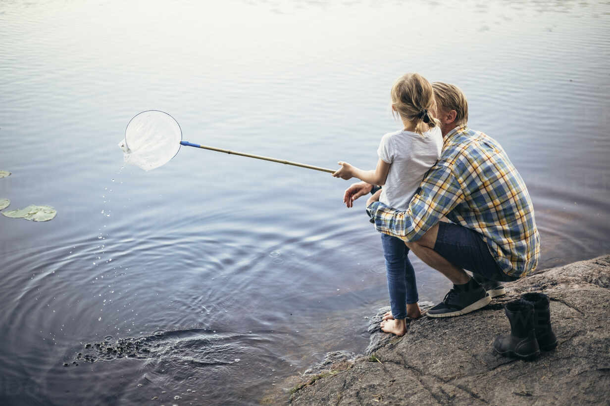 High angle view of father and daughter fishing in lake stock photo