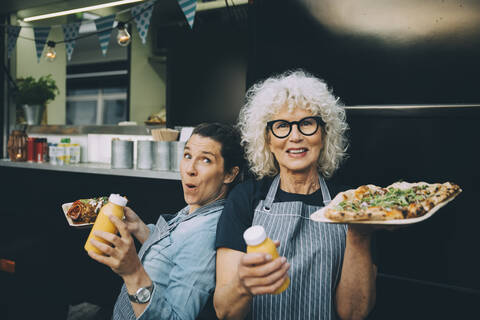 Portrait of senior owner with assistant holding street food in city stock photo