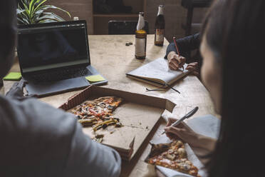 Kollegen arbeiten an der Programmierung, während sie am Arbeitsplatz Pizza essen - MASF20304