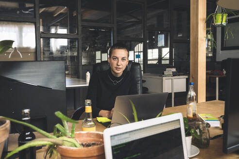 Portrait of businesswoman working over laptop at workplace - MASF20339