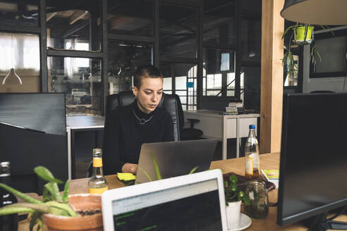 Businesswoman working over laptop at workplace - MASF20342