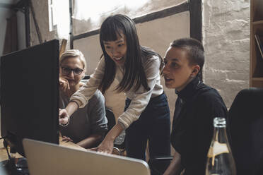 Smiling entrepreneur discussing with coworkers at workplace - MASF20350