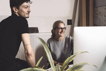 Smiling computer programmer with coworker at workplace - MASF20370