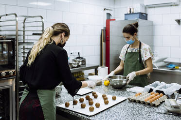Bäckerinnen backen Kekse in der Küche einer Bäckerei während COVID-19 - XLGF00665