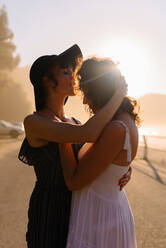 Delighted lesbian couple cuddling during sundown - ADSF16953
