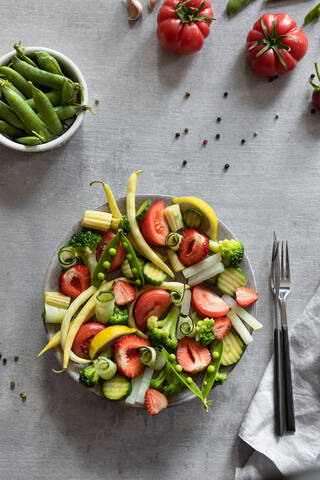 Top view of delicious healthy tomatoes and cucumbers placed on plate with peas and green beans on table in kitchen stock photo