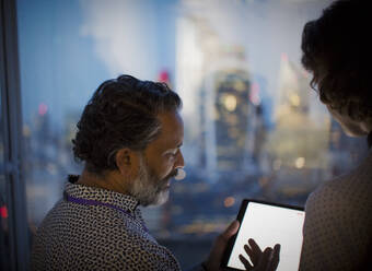 Business people with digital tablet working late at office window - CAIF29722