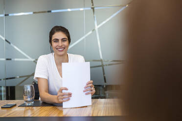 Porträt einer selbstbewussten lächelnden Geschäftsfrau mit Papierkram in einer Besprechung - CAIF29756