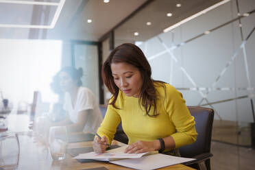 Businesswoman with paperwork in conference room meeting - CAIF29757