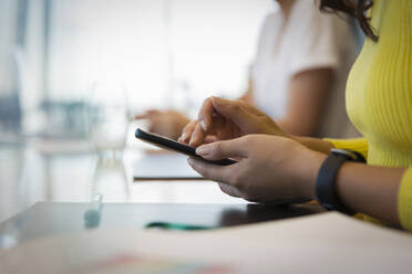 Close up businesswoman using smart phone in meeting - CAIF29759