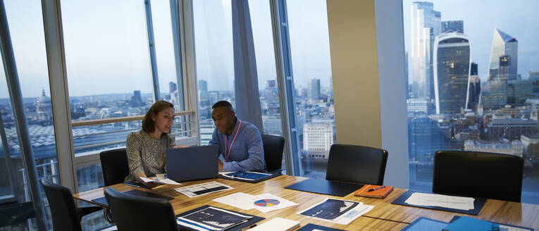 Business people working at laptop in highrise conference room meeting - CAIF29765