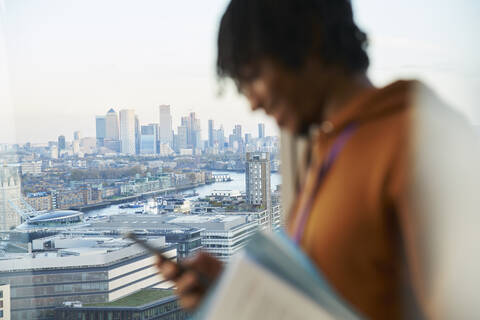 Businessman using smart phone at highrise window, London, UK stock photo