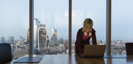 Businesswoman using laptop in highrise office, London, UK - CAIF29793