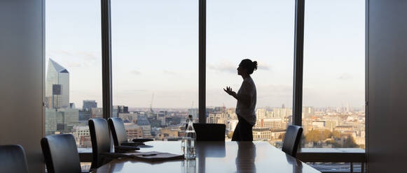 Businesswoman preparing for meeting in highrise conference room - CAIF29800