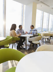 Business people talking in sunny office cafeteria - CAIF29803