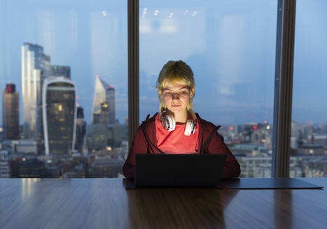 Geschäftsfrau, die noch spät am Laptop in einem Hochhausbüro arbeitet, London, UK - CAIF29804