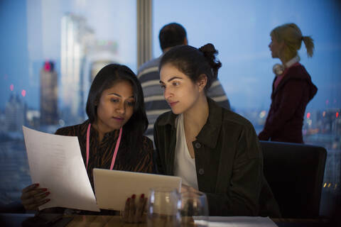 Businesswomen with digital tablet working late in office stock photo