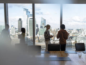 Geschäftsleute im Gespräch am Fenster eines Hochhausbüros, London, UK - CAIF29813