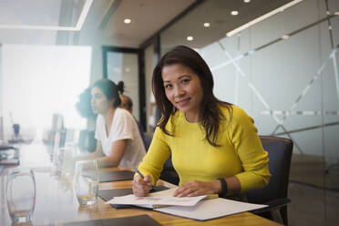 Portrait smiling businesswoman with paperwork in conference room meeting - CAIF29821