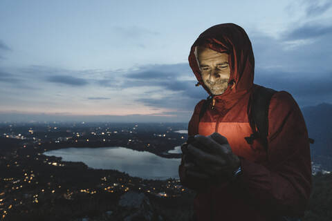 Mature male hiker using mobile phone against sky at twilight stock photo