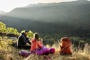 Couple sitting looking at view while drinking coffee in forest - VEGF03016