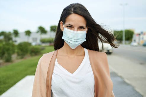 Junge Frau mit Gesichtsschutzmaske auf der Straße - KIJF03357