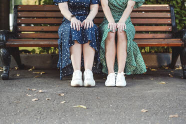 Freundinnen sitzen auf einer Bank im Park - VYF00188