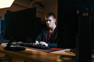 Young computer hacker working while sitting at office - JRFF04784