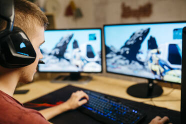 Junger Mann spielt Videospiele mit Computer am Schreibtisch - JRFF04790
