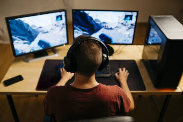 Junger Mann spielt Videospiele mit Computer am Schreibtisch - JRFF04791