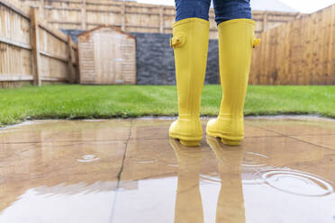 Close-up of woman standing in back yard during rainy season - WPEF03485