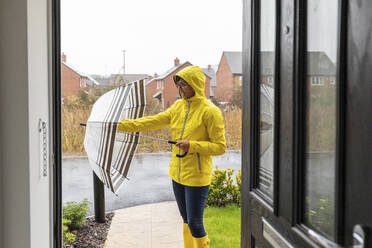 Mid adult woman closing umbrella before going at home - WPEF03494