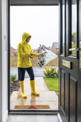 Frau schließt Regenschirm im Hinterhof stehend, bevor sie nach Hause geht - WPEF03495