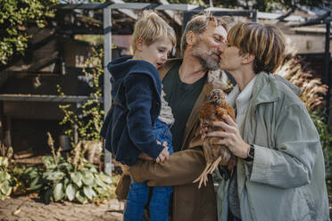 Family with chicken coop standing in back yard - MFF06616