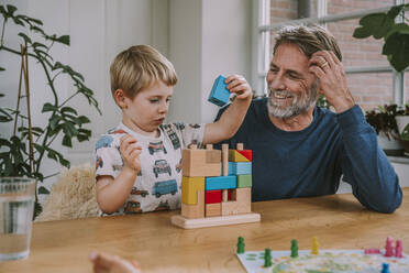 Father watching son playing with puzzle while sitting at home - MFF06652