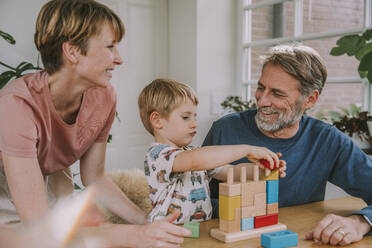 Mother and father playing with son toy block puzzle at home - MFF06654