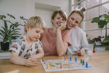 Mütter schauen zu, während ihr Sohn zu Hause ein Brettspiel spielt - MFF06660