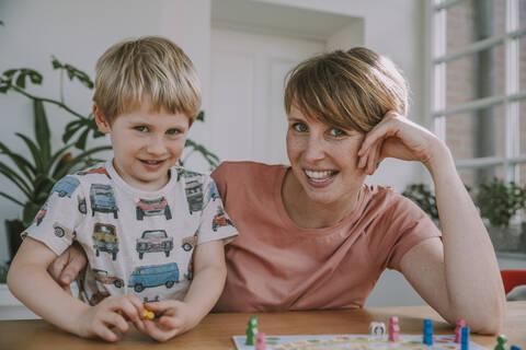 Mother playing with son board game at home stock photo