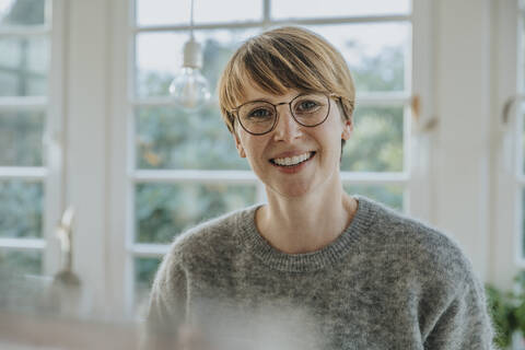 Lächelnde Frau im mittleren Erwachsenenalter, die zu Hause steht, lizenzfreies Stockfoto