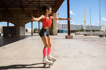 Concentrated female roller skating on sports ground on sunny day in city - ADSF17068