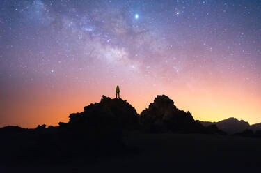 Silhouette eines Mannes von Wanderern, der auf einem dunklen Felsen vor einem sternenklaren Nachthimmel in langer Belichtung auf Teneriffa steht - ADSF17125