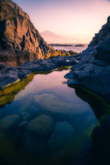 Szenische Ansicht eines kleinen Teiches mit transparentem Wasser vor dem Hintergrund der Meereslandschaft und des Sonnenuntergangs auf Teneriffa - ADSF17126