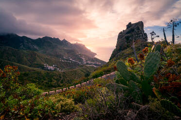 Malerische Landschaft mit felsigen Bergen, die mit verschiedenen grünen Pflanzen bedeckt sind, vor dem Hintergrund eines erstaunlichen Sonnenuntergangs auf Teneriffa - ADSF17130