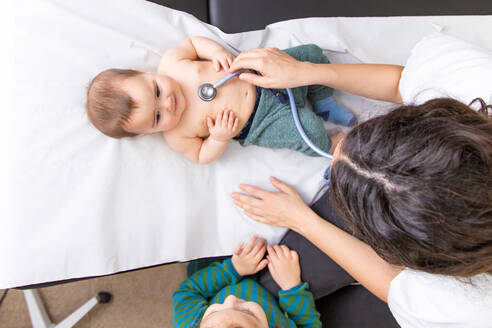 Kleines schönes Baby, das von einer Kinderärztin mit einem Stethoskop medizinisch untersucht wird - ADSF17141