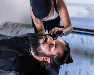 Von oben von der Ernte nicht erkennbare Friseurin mit Haarkamm in der Hand Rasierbart einer stilvollen brutalen Kundin mit Schnurrbärten im Friseursalon - ADSF17144