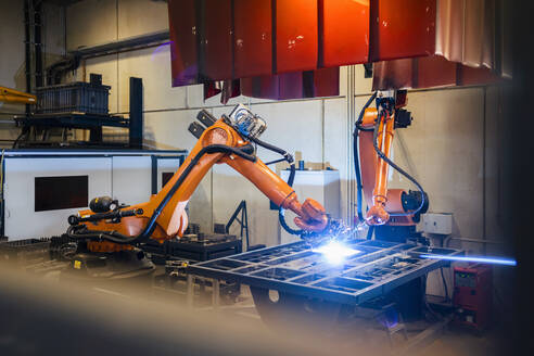 Orangefarbene Roboterarme schweißen in der Industrie - DIGF12931