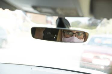 Reflection of mature woman wearing protective face mask sitting in car - PMF01445