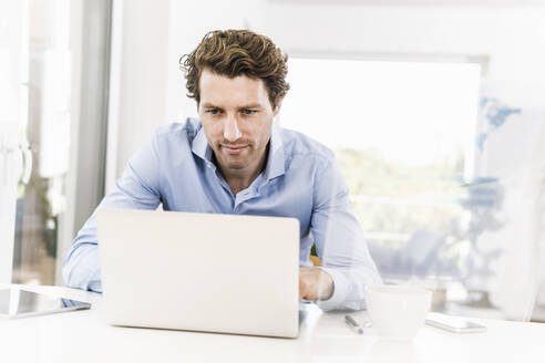 Mittlerer erwachsener Mann arbeitet an einem Laptop im Büro - UUF21887